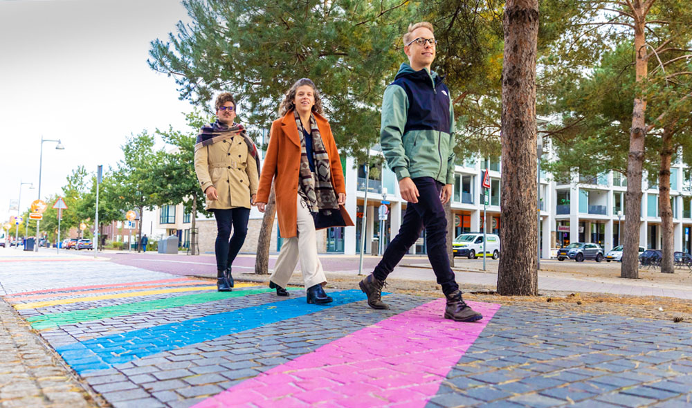 Drie leden van de werkgroep wandelen over het regenboopad bij Apeldoorn Centraal Station