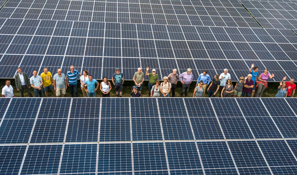 Participanten van het zonnepark staan tussen de panelen