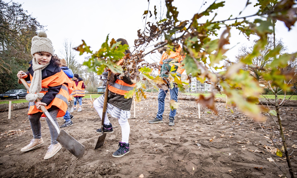 Kinderen helpen mee met het planten van bomen